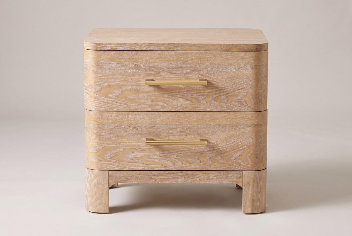 Lodi nightstand in Natural, straight front view: two drawers with brushed-gold bar pulls, rounded corners, four block legs