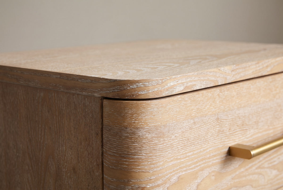 Close-up of the Lodi top corner: the rounded top slab, the drawer front curving round the corner and a brushed-gold pull