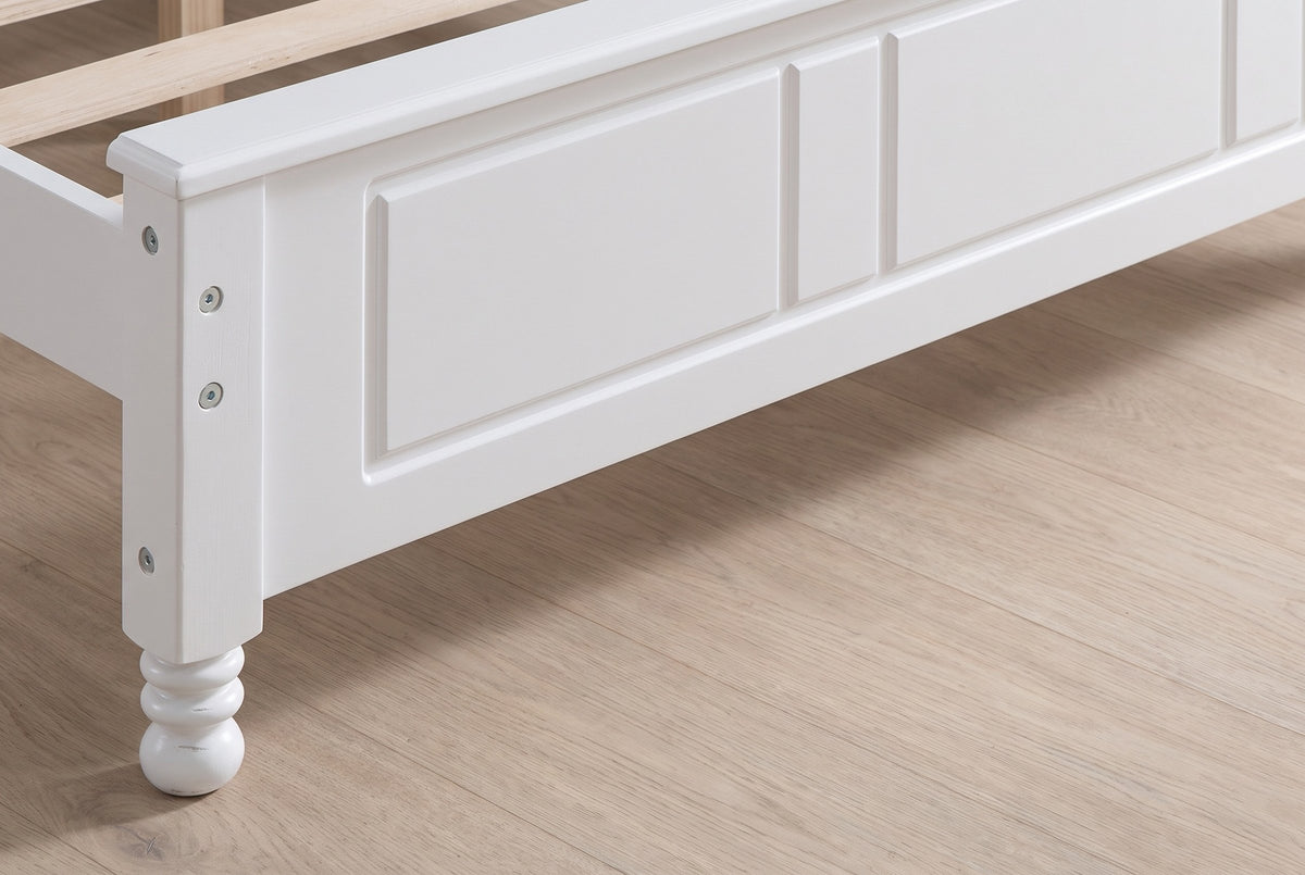 Close-up of the Loreto footboard corner: square post with round bolt heads and a turned bun foot