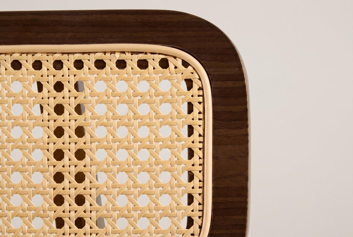 Close-up of the Lovere back panel: a walnut-veneer frame around a flat cane-look weave