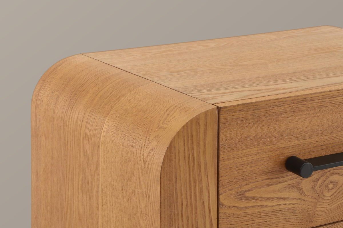 Close-up of the rounded waterfall corner in the brown wood finish, the seam to the flat top and the end of a black bar handle