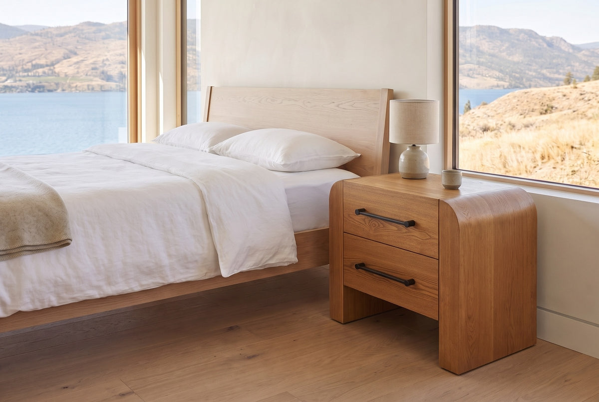 Macerata nightstand in brown beside a pale oak bed in a lake house bedroom with a view of the lake and hills