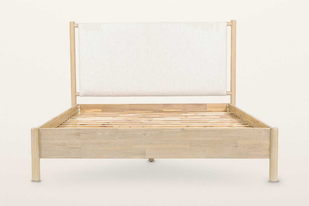 Manciano bed, raised front view on a warm white studio backdrop: the cushion headboard hanging between the two tall round hea