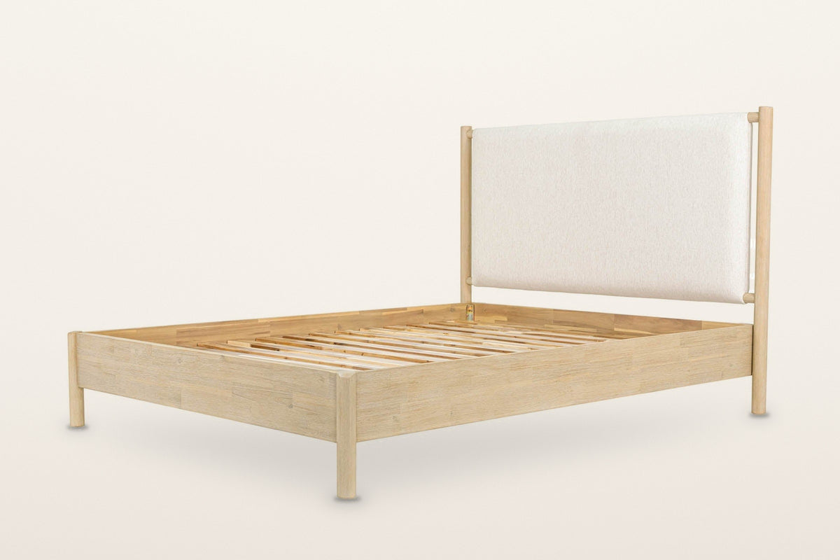 Manciano bed frame in light natural wood, three-quarter view on a warm white studio backdrop: four round posts