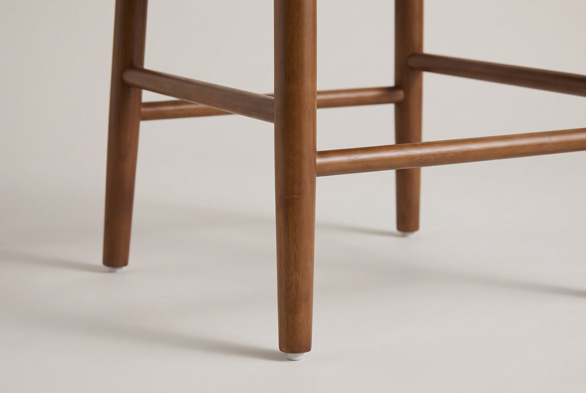 Close-up of a Menaggio tapered walnut-finish leg with its small white non-slip floor protector and the round stretchers joini