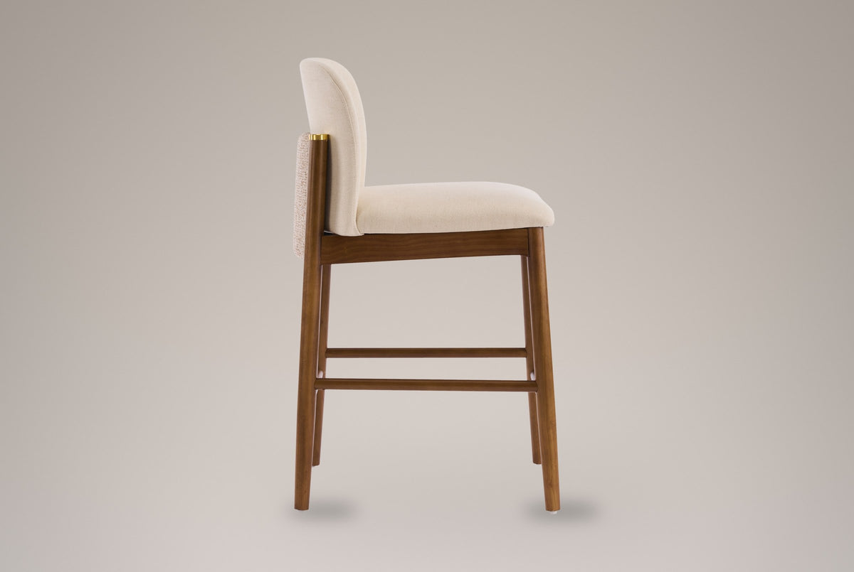 Side view of the Menaggio counter stool: curved beige back, textured back panel between the rear posts, thick seat