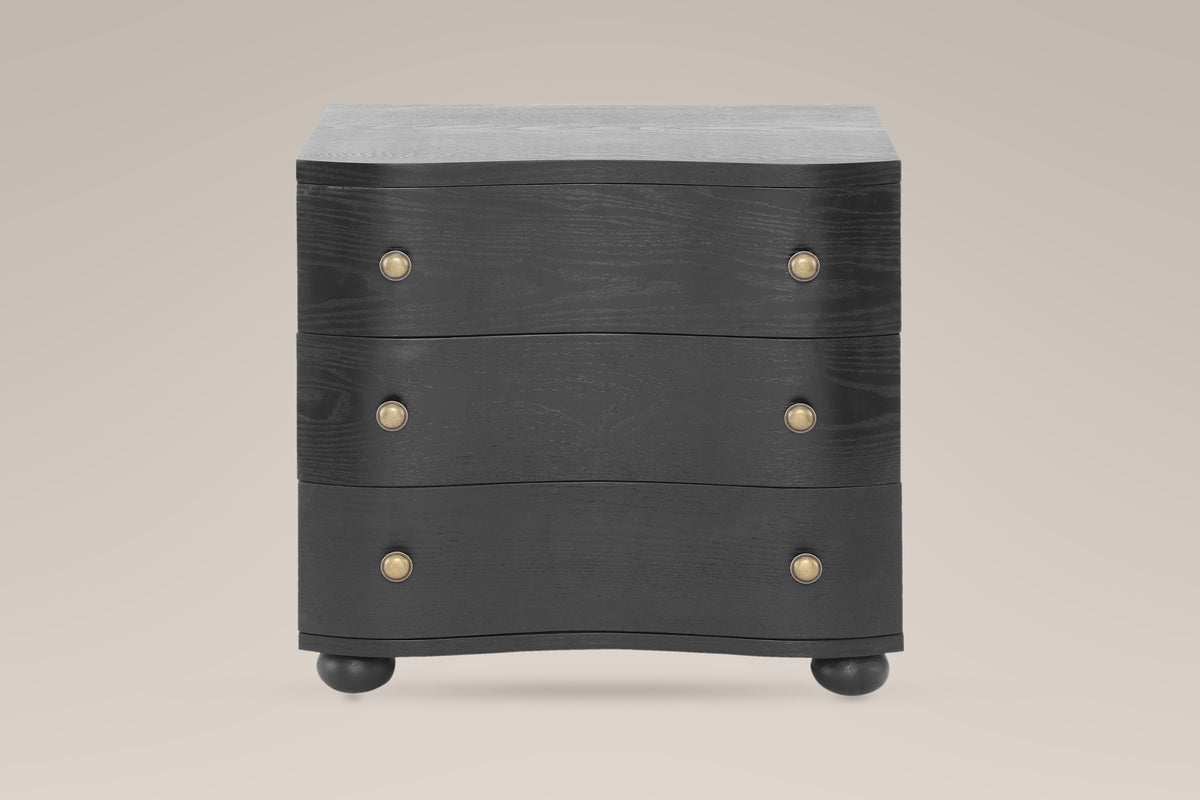 Merano nightstand in Black, straight front view: three wave-front drawers, six round brass knobs, four bun feet