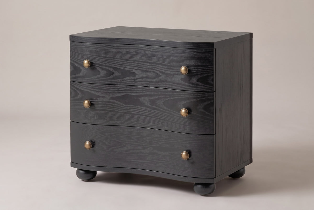 Merano 3-drawer nightstand in Black ash, three-quarter view on a warm grey studio backdrop