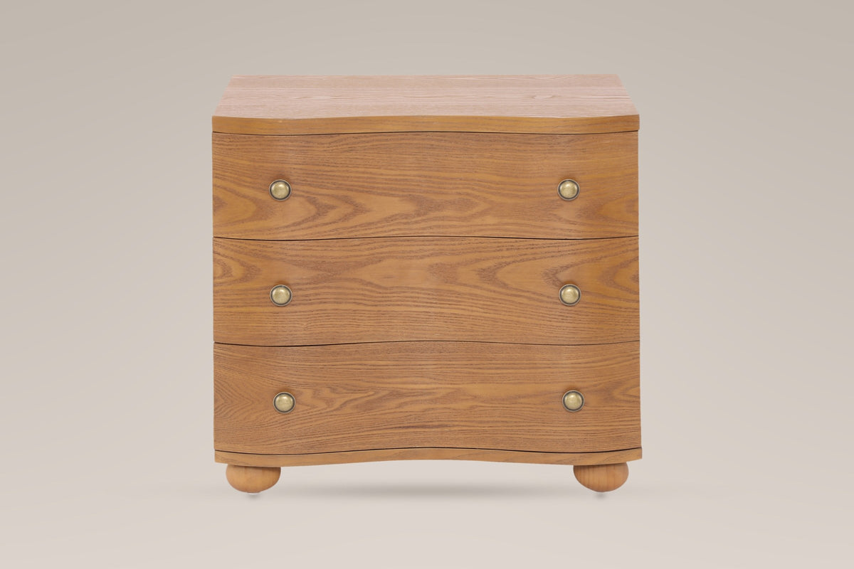 Merano nightstand in Honey Brown, straight front view: three wave-front drawers, six round brass knobs, four bun feet
