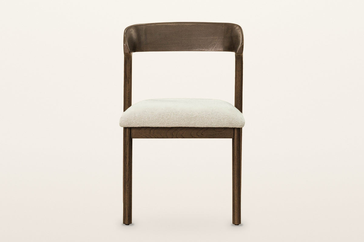 Mondavio dining chair, straight front view on a warm white studio backdrop: the curved back band above an open gap and the Iv