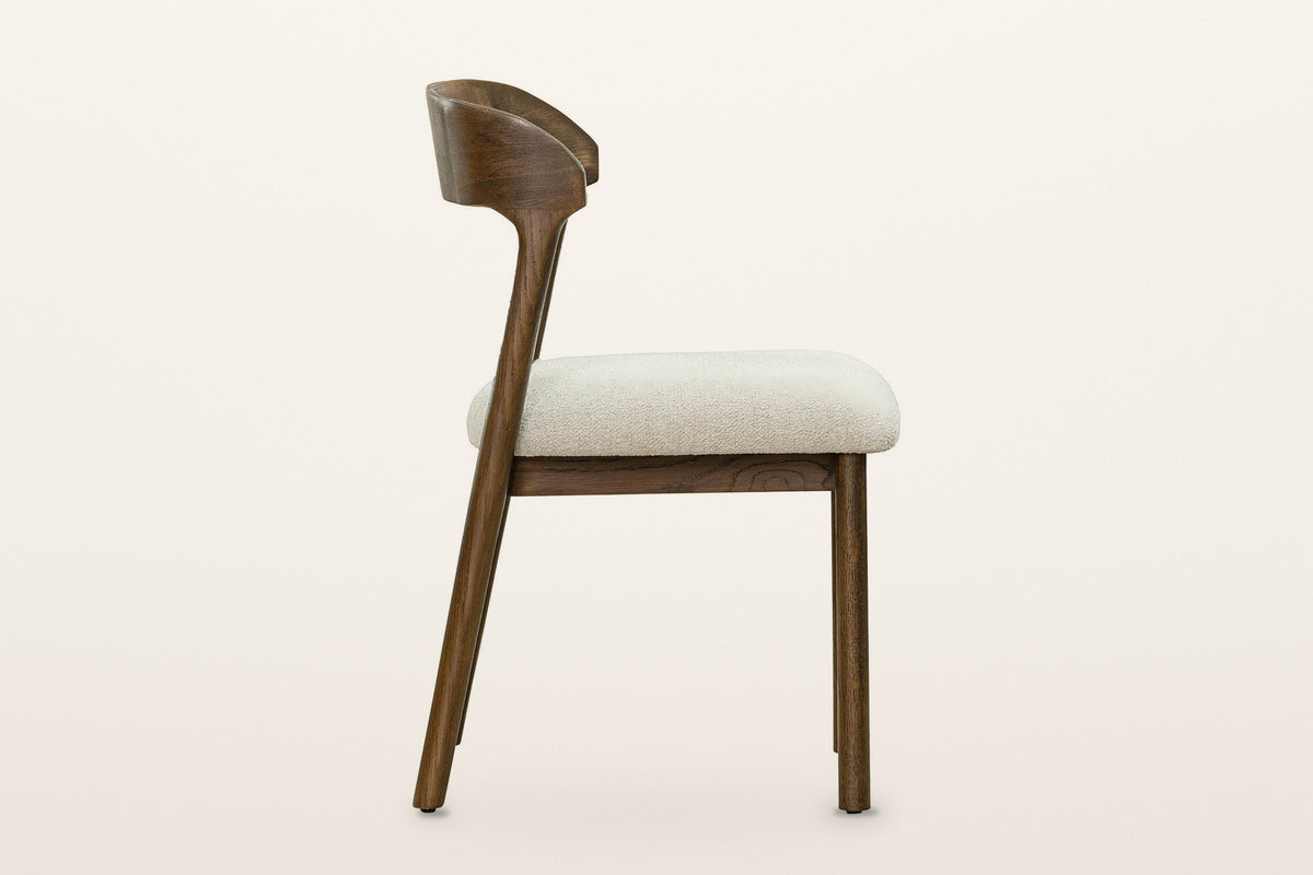 Mondavio dining chair, side view on a warm white studio backdrop: the rear legs rake back and run up into the curved back ban