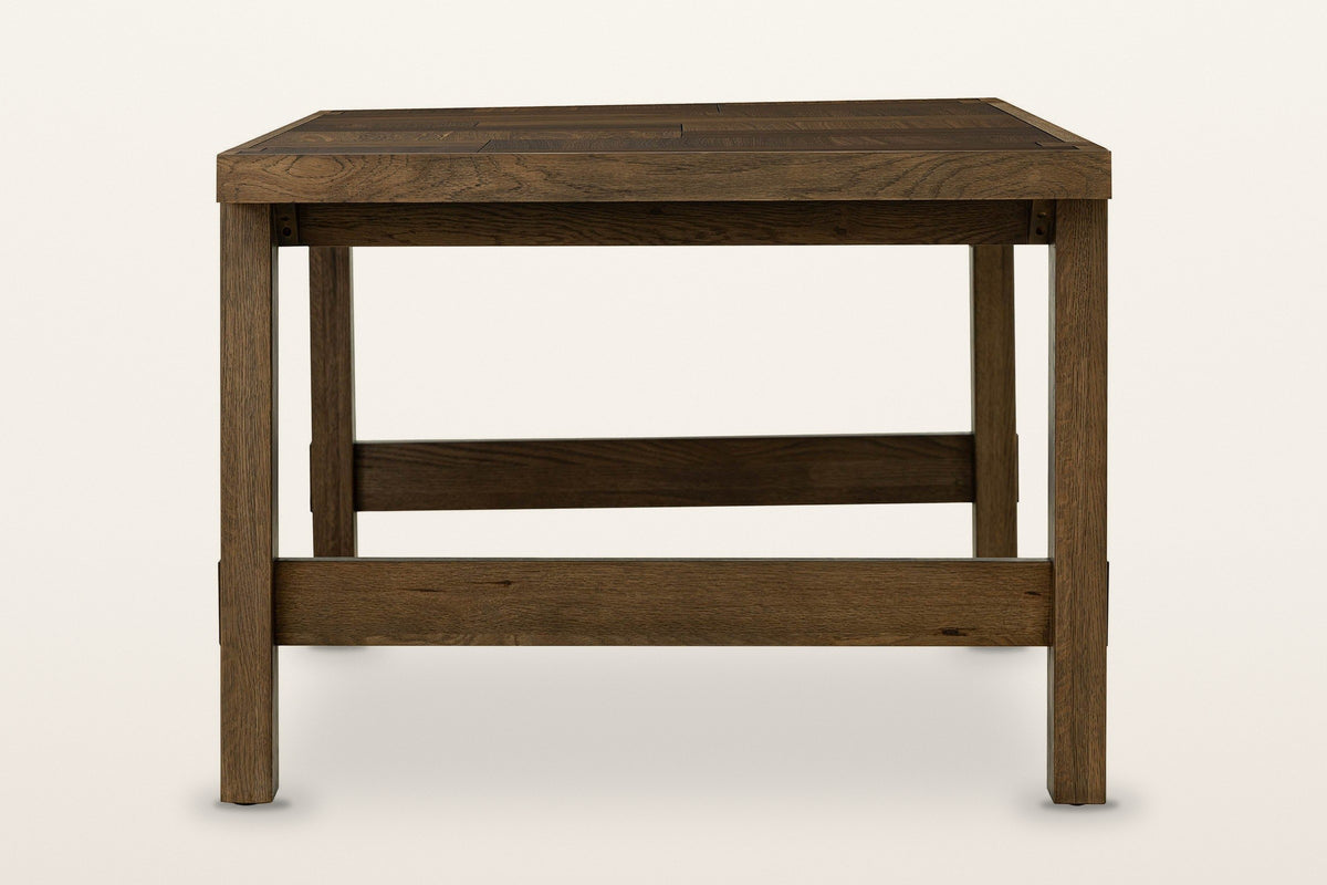 Mondavio dining table in Smokey Chestnut, end view on a warm white studio backdrop: two flat legs