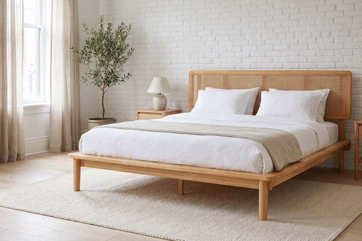 Montalcino cane bed made up with white linen against a white brick wall in a bright bedroom with an olive tree
