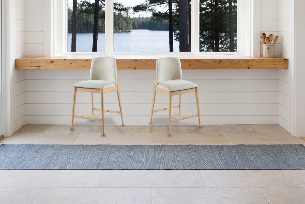 Two Monteriggioni counter stools in front of a pine counter and a window onto a lake in a white shiplap Muskoka cottage