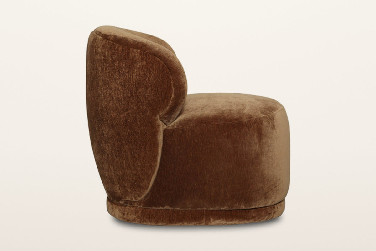 Monterubbiano accent chair in Bronze velvet, side view on a warm white studio backdrop: the back wraps round and runs down th