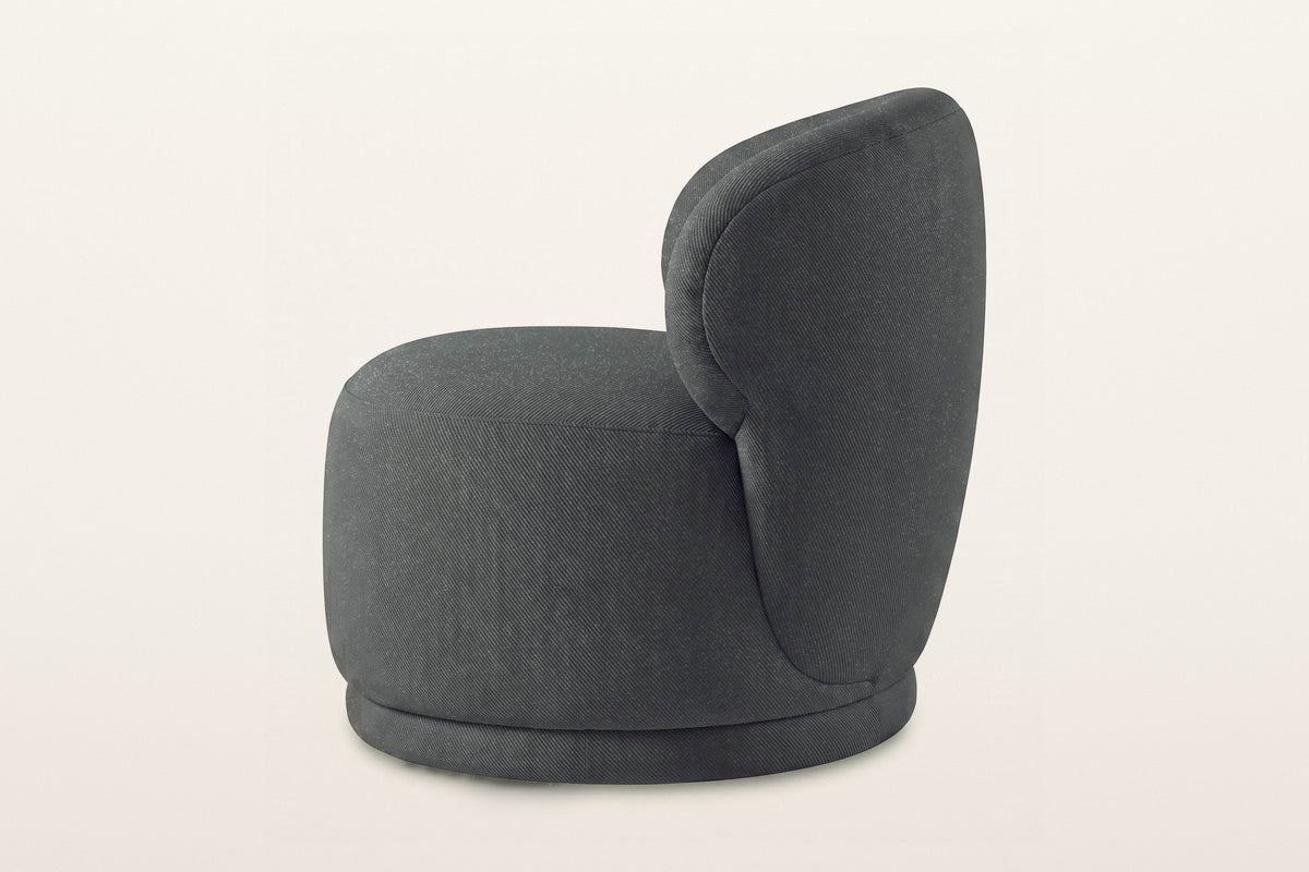 Monterubbiano accent chair in Charcoal twill, side view on a warm white studio backdrop: the back wraps round and runs down t