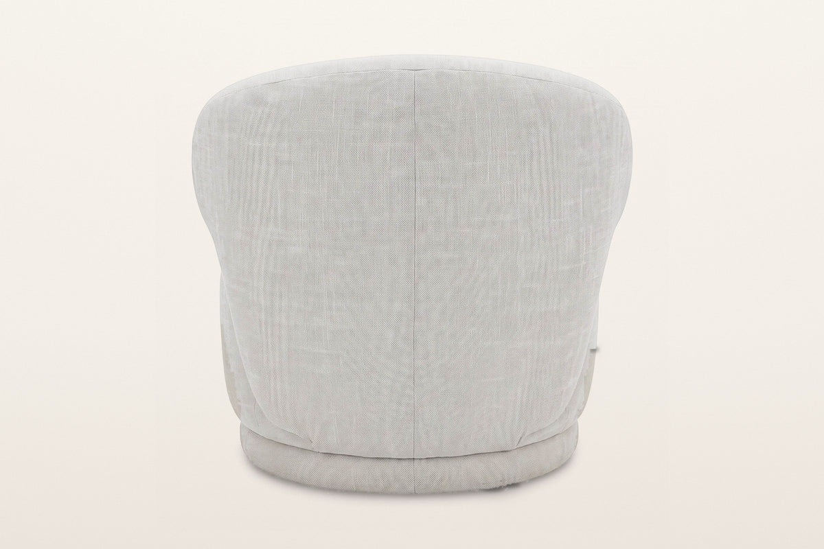 Back of the Monterubbiano accent chair in Ivory twill on a warm white studio backdrop: one smooth curved shell with a centre