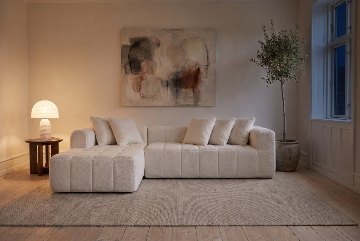 Nembo Boucle Cloud Sectional in the same Copenhagen living room at night, the paper table lamp lit and the window dark