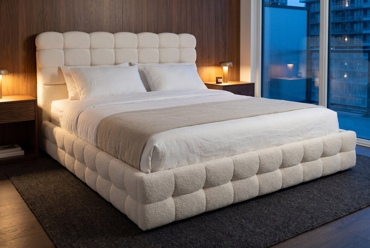 Nemi bed against walnut wall panels in a Toronto condo at dusk, two small lamps lit and the city in the window