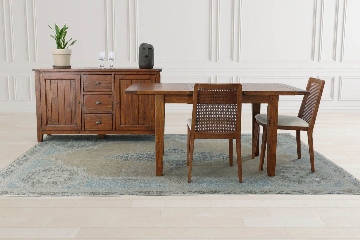 Novella sideboard behind a small dining table and chairs in a panelled room