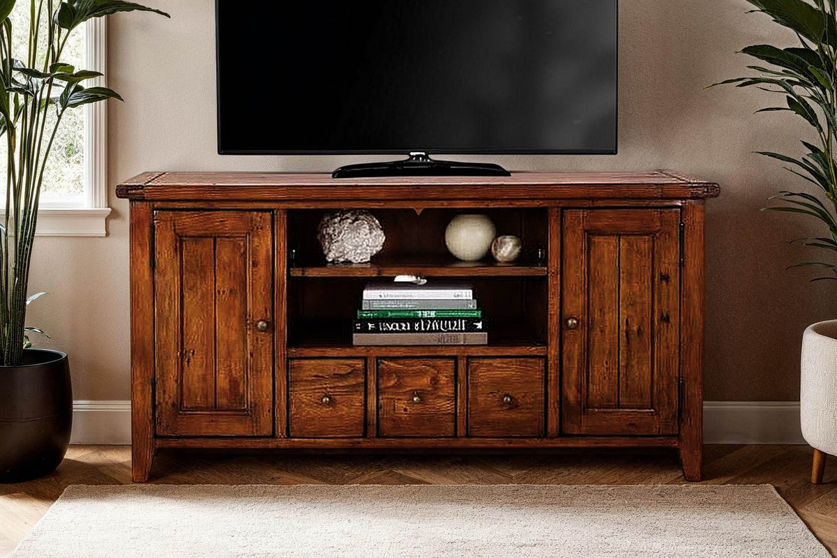 Novella media console holding a TV, books and decor between two tall plants