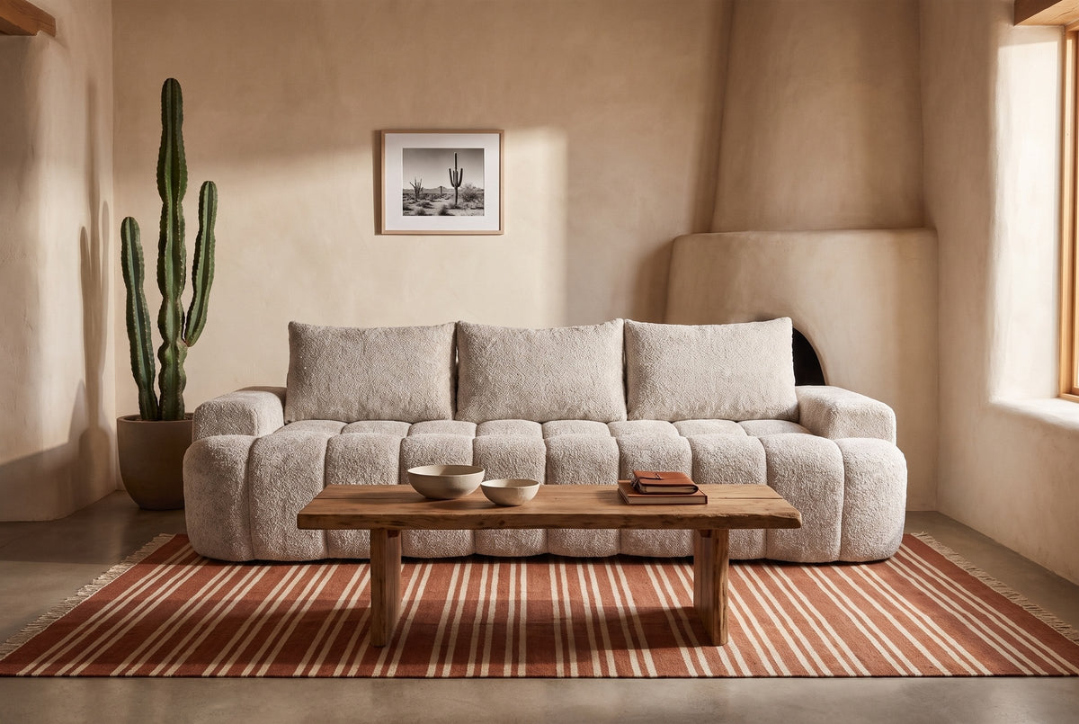 The Nuvola sofa in Camel in an adobe living room in Arizona, with a striped rust and cream rug and a mesquite coffee table