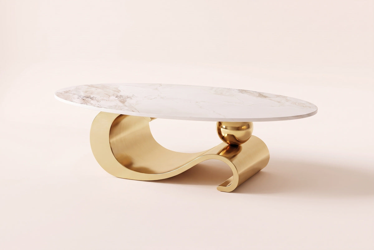The Ondina coffee table in Gold, front view: a white veined sintered stone oval on one polished gold steel ribbon that curls, dips and scrolls, with a gold sphere resting on it, on an off-white studio background