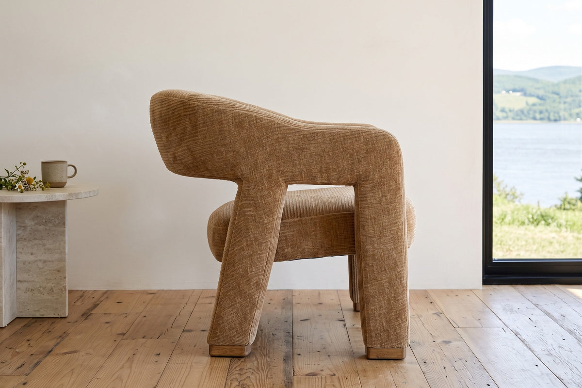 Opi accent chair in side profile in a Baie-Saint-Paul house, with warm-white limewash and a window to the St.