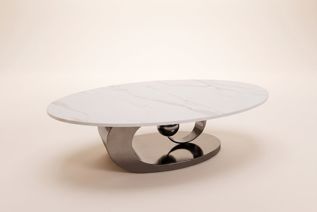 The Oriana coffee table in Gray seen from a low side angle, showing the slim stone edge and the gunmetal ring and sphere beneath it, on an off-white studio background