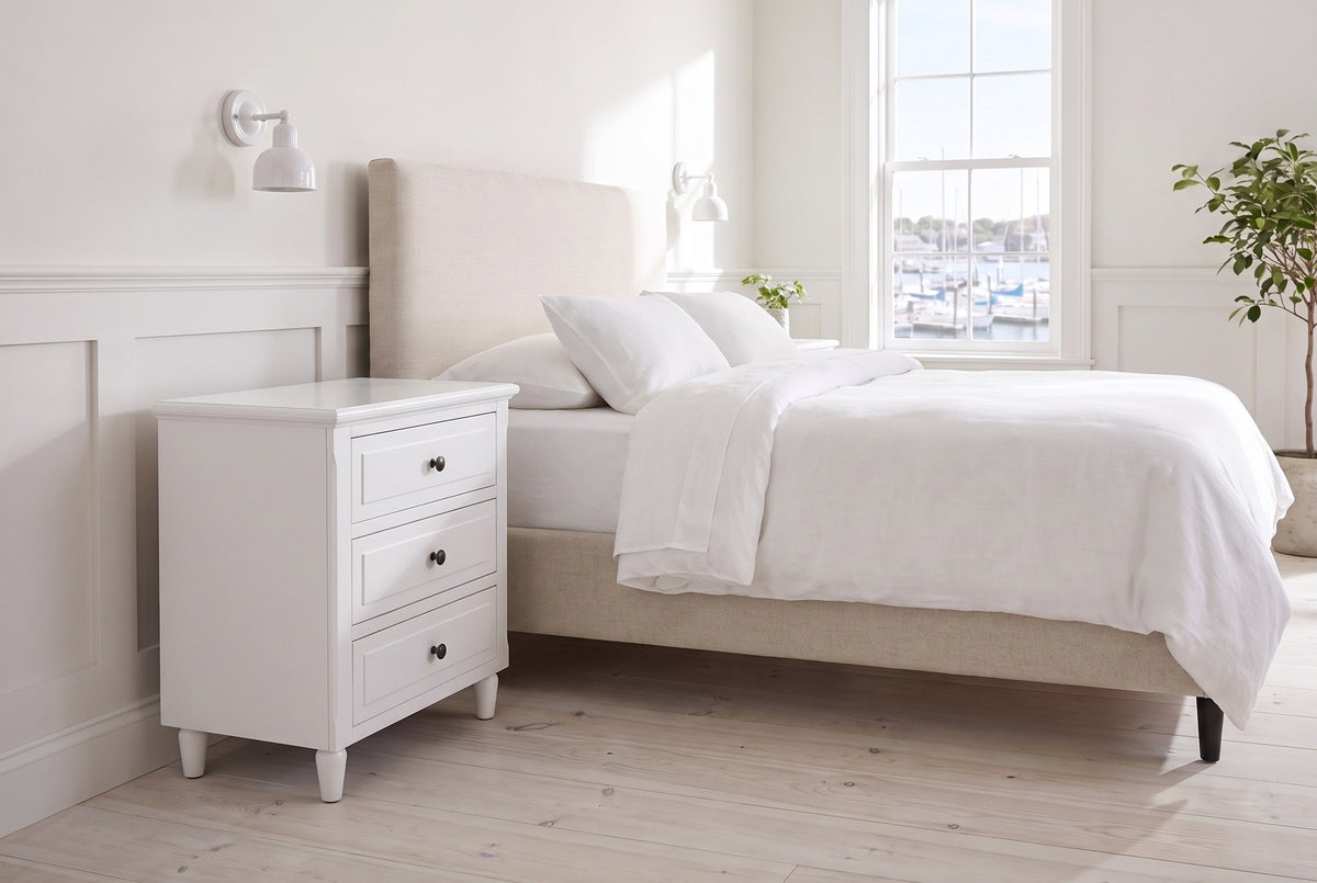 Ortona nightstand in White beside a bed with white linen in a bright Halifax bedroom with a harbour view