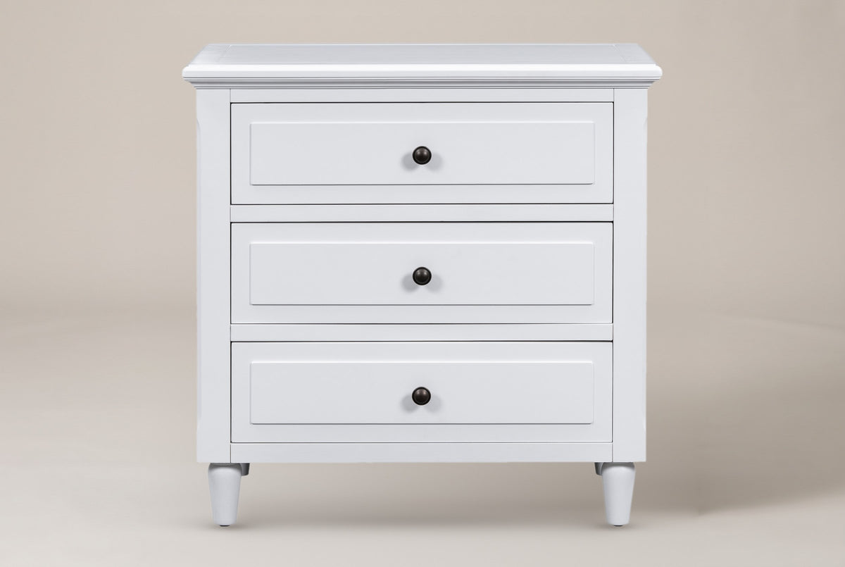 Ortona nightstand in White, straight front view: moulded top, three drawers with round bronze-tone knobs, four turned legs