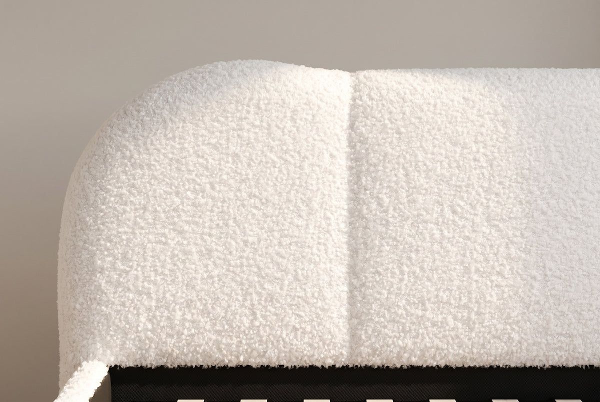 Close-up of the white teddy bouclé headboard: its rounded corner and one seam
