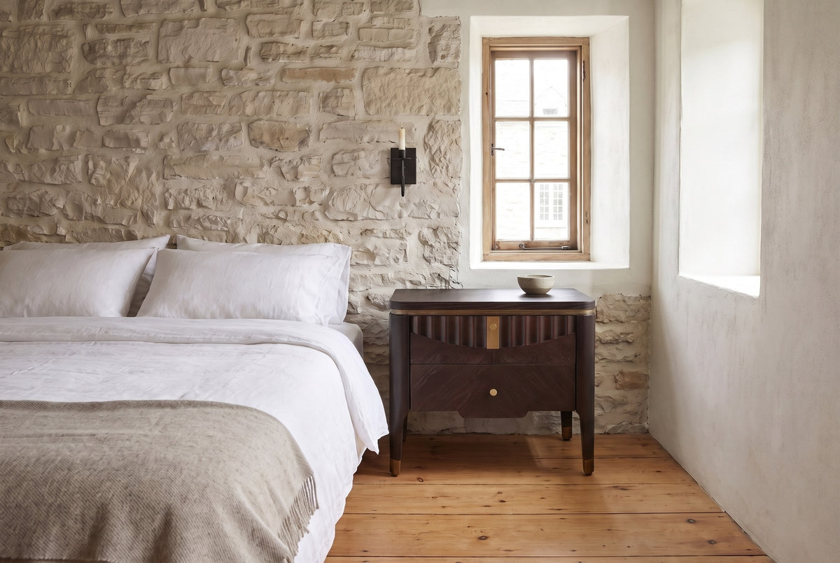 Pavia nightstand in Dark Brown beside a bed against a limestone wall in an old Quebec City house