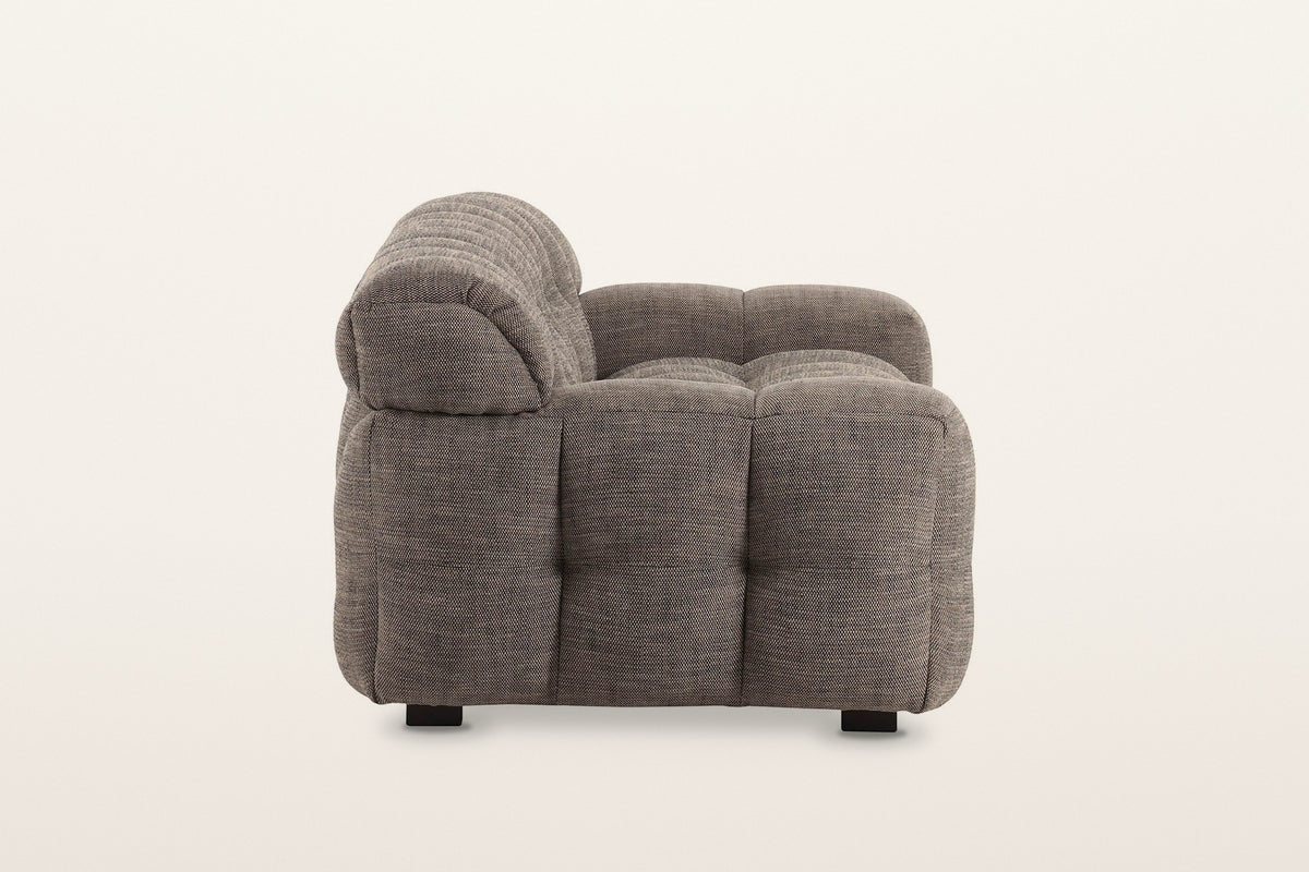 Pergola sofa in Brown, side view on a warm white studio backdrop: a round roll at the end of the back above the low puffed ar