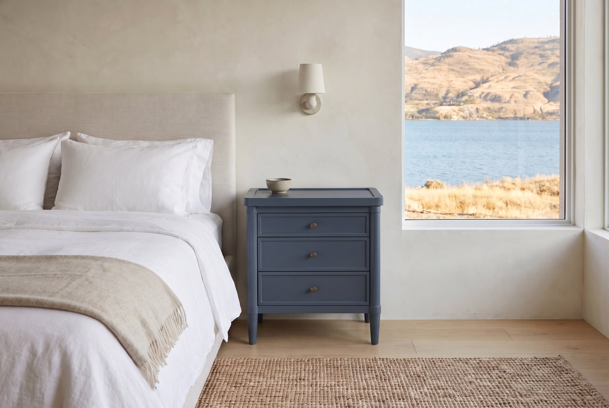 Pescara nightstand in Navy Blue beside a bed in a Kelowna lake house bedroom with a view of the lake and dry hills