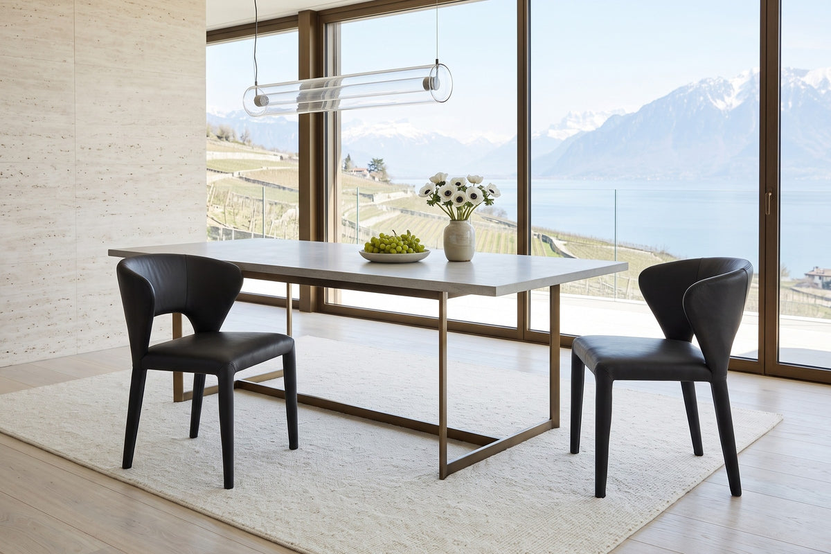 Two Petralia dining chairs in Black leather at the corner of a limestone table on a bronze frame in a Montreux villa