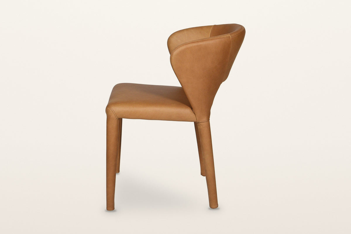 Petralia dining chair in Brown leather, side view on a warm white studio backdrop: the back leans back and the rear legs rake