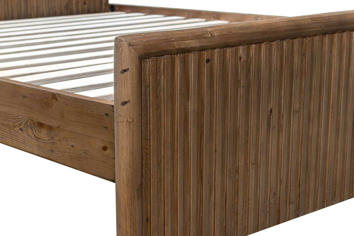 Close-up of the Pettorano footboard corner: the round top rail curving down into a round corner post above the reeded panel
