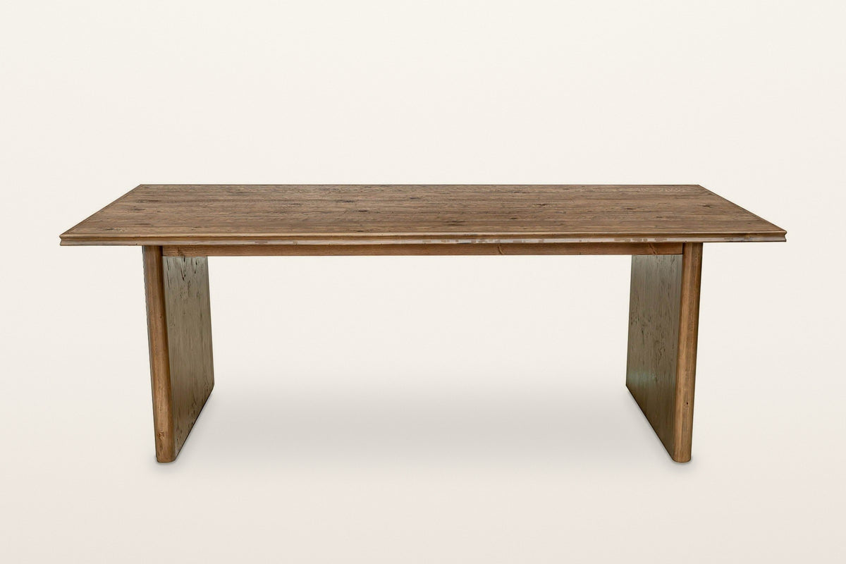 Pettorano dining table in Brown, straight front view on a warm white studio backdrop: a long planked top with a stepped edge