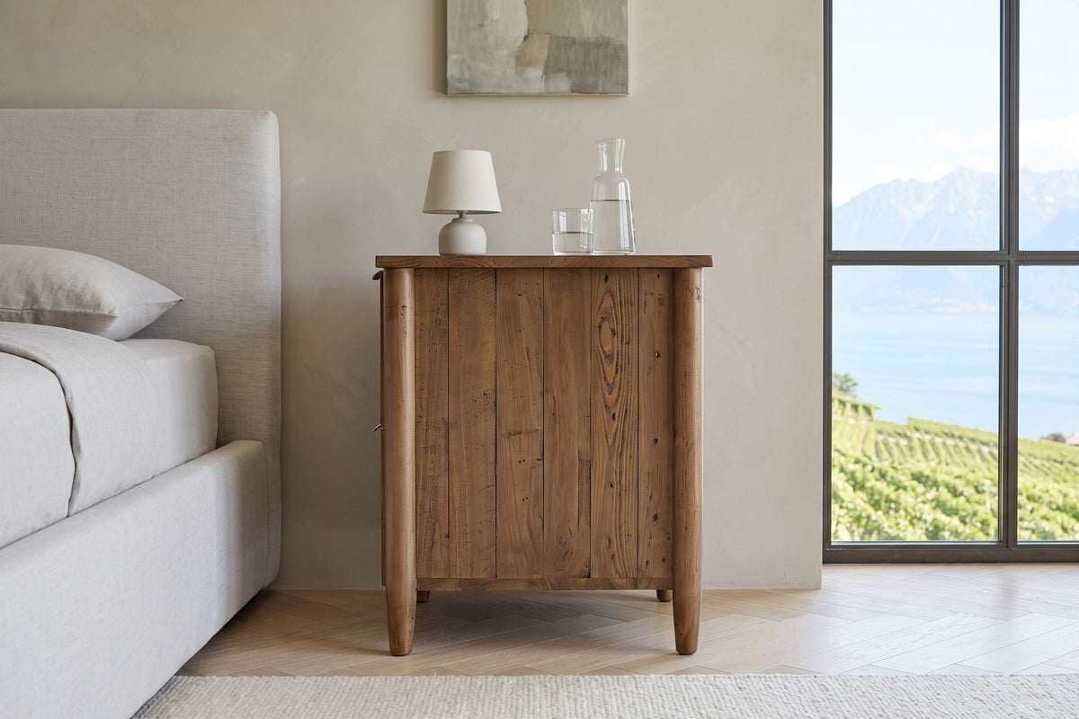 Side view of the Pettorano nightstand in Brown reclaimed pine in a Vevey villa bedroom, with greige plaster