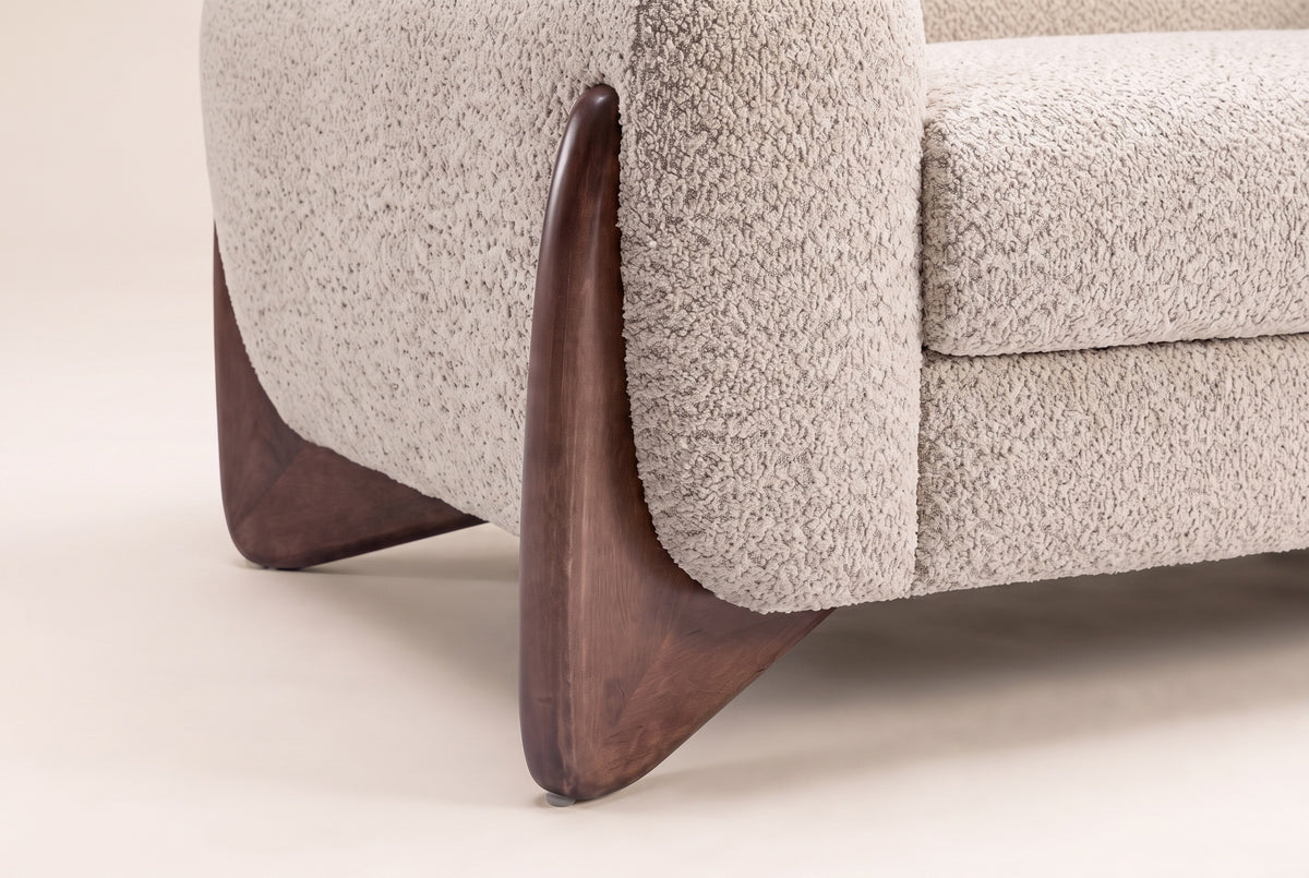 Close-up of a walnut-finish wooden wedge foot at the corner of the boucle arm