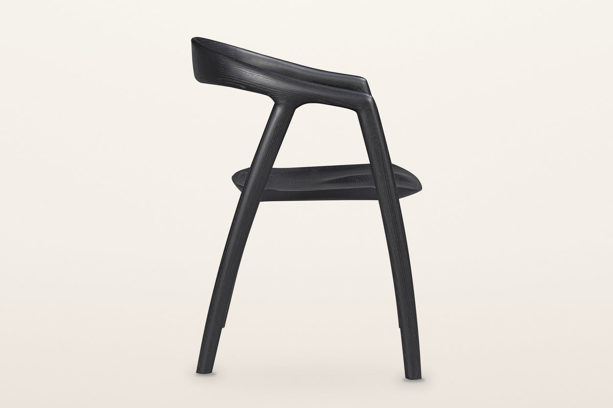 Pollica dining chair in Black, side view on a warm white studio backdrop