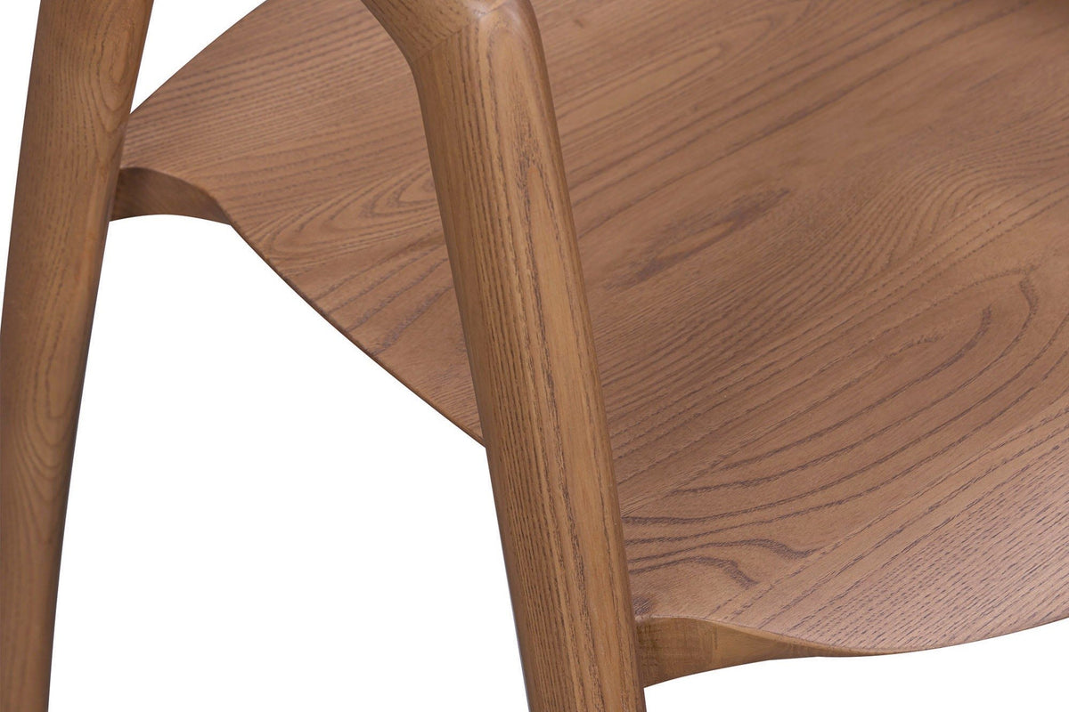 Close-up of the Pollica seat in Caramel ash: the dished solid seat with open ash grain, and a front leg