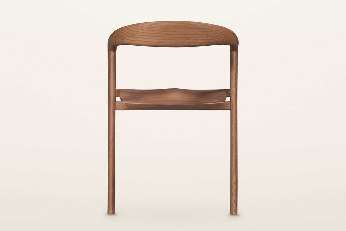 Pollica dining chair in Caramel from behind on a warm white studio backdrop: the back is open under the curved band