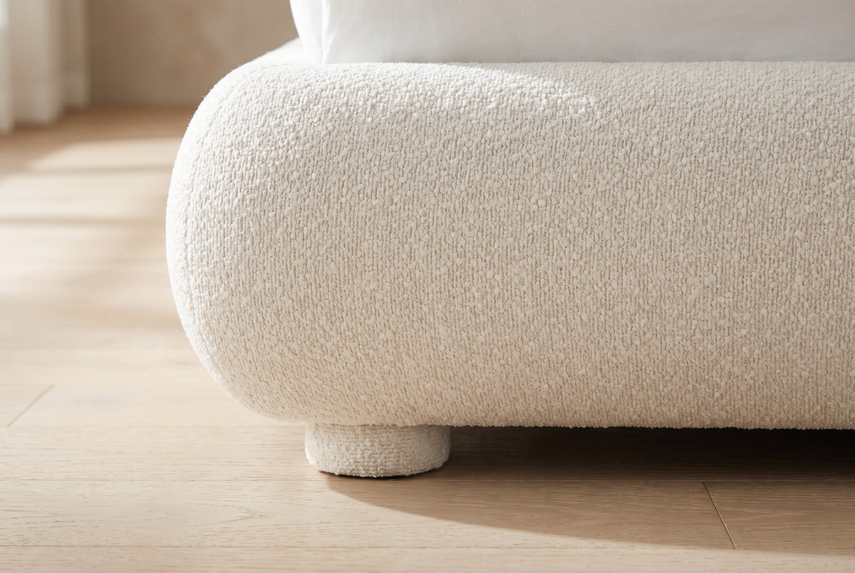 Close-up of the rounded foot rail and a short round boucle foot on an oak floor