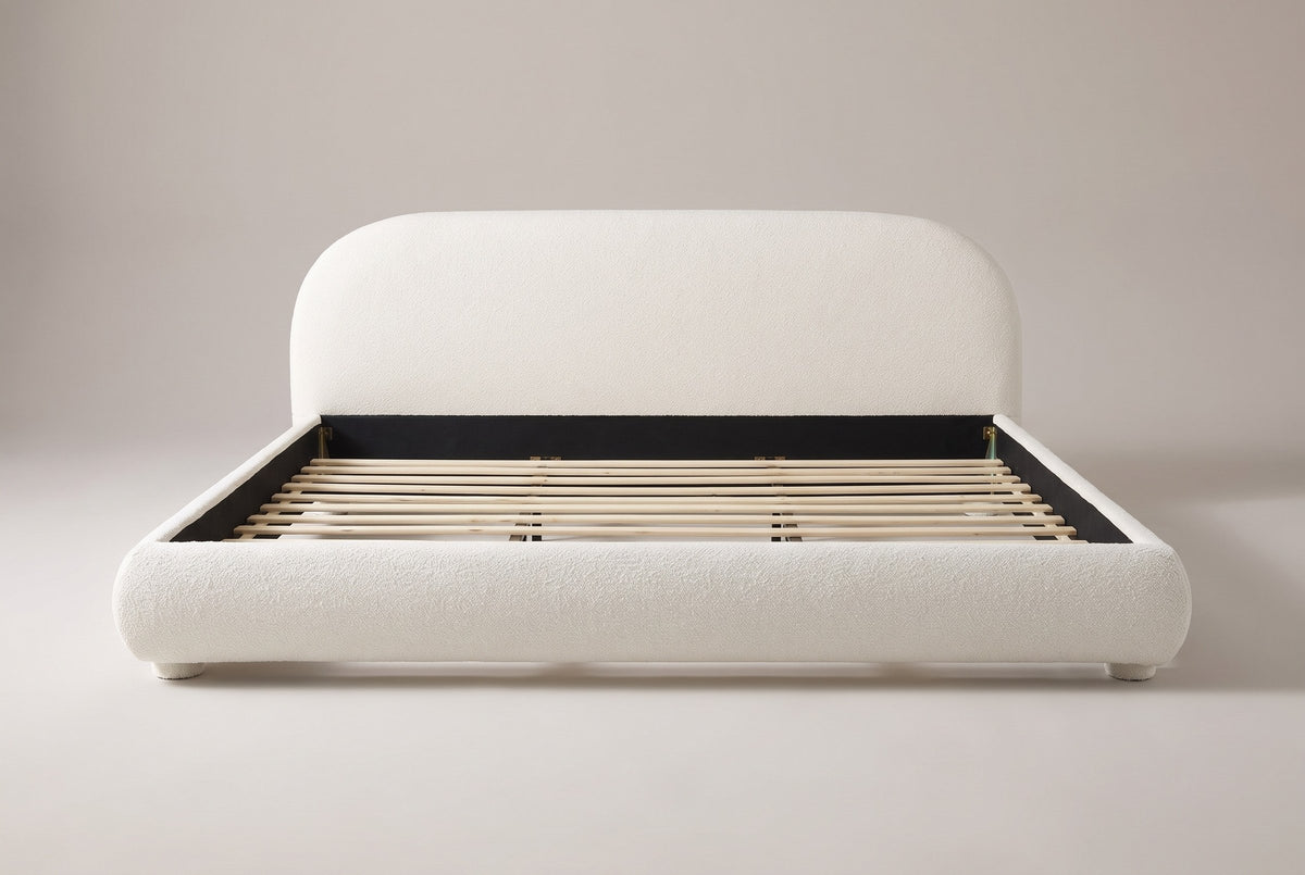 Pollutri upholstered bed in cream white boucle, straight front view on a studio backdrop
