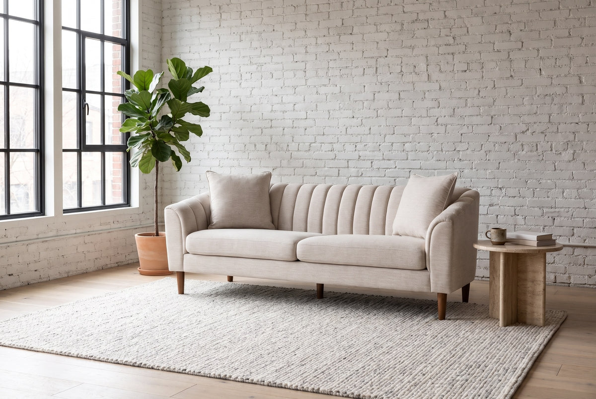 Prato sofa against a white brick wall in a Montreal loft, steel windows and a fig tree beside it