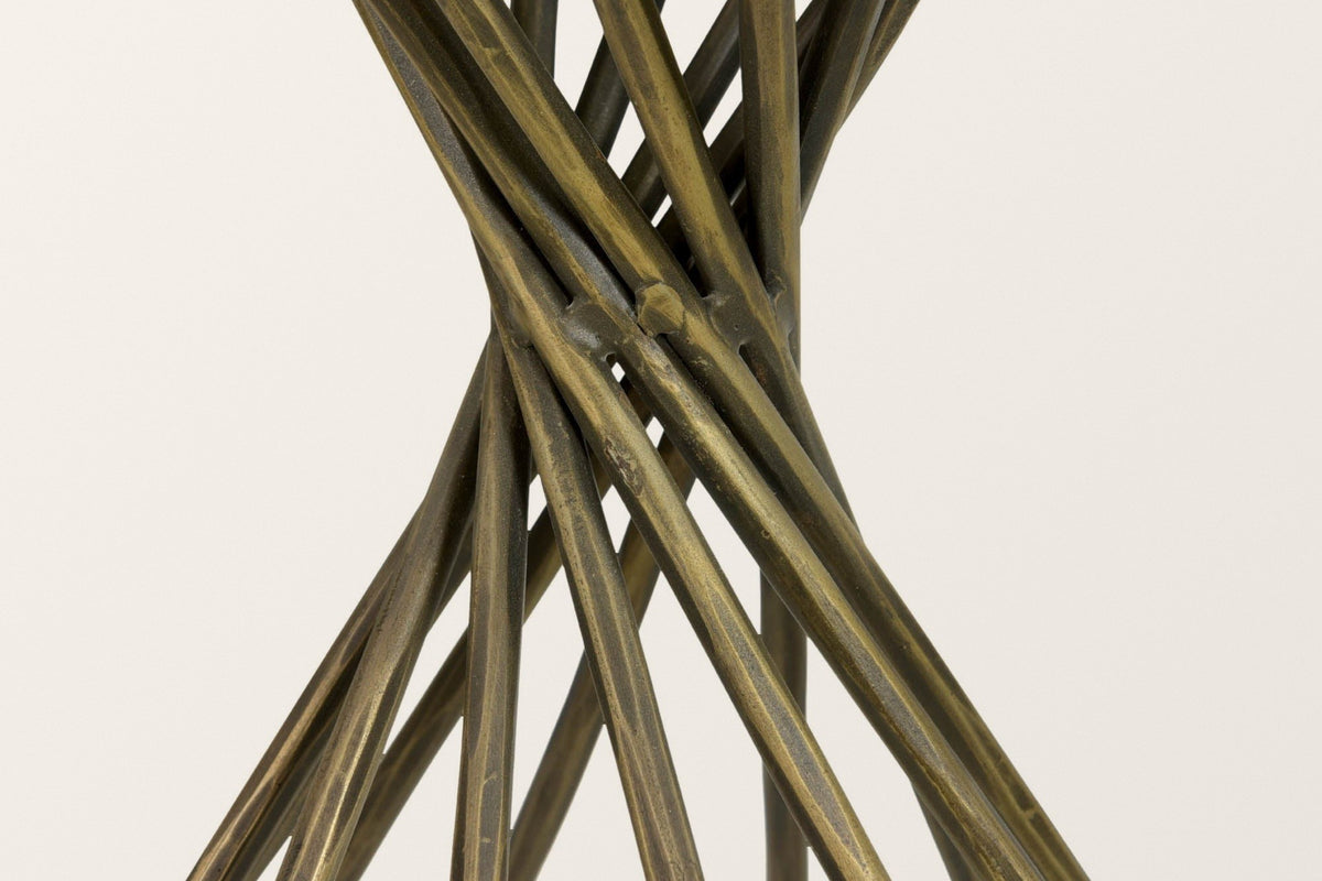 Close-up of the Rango base: faceted metal rods in an antique brass finish crossing at the pinched waist