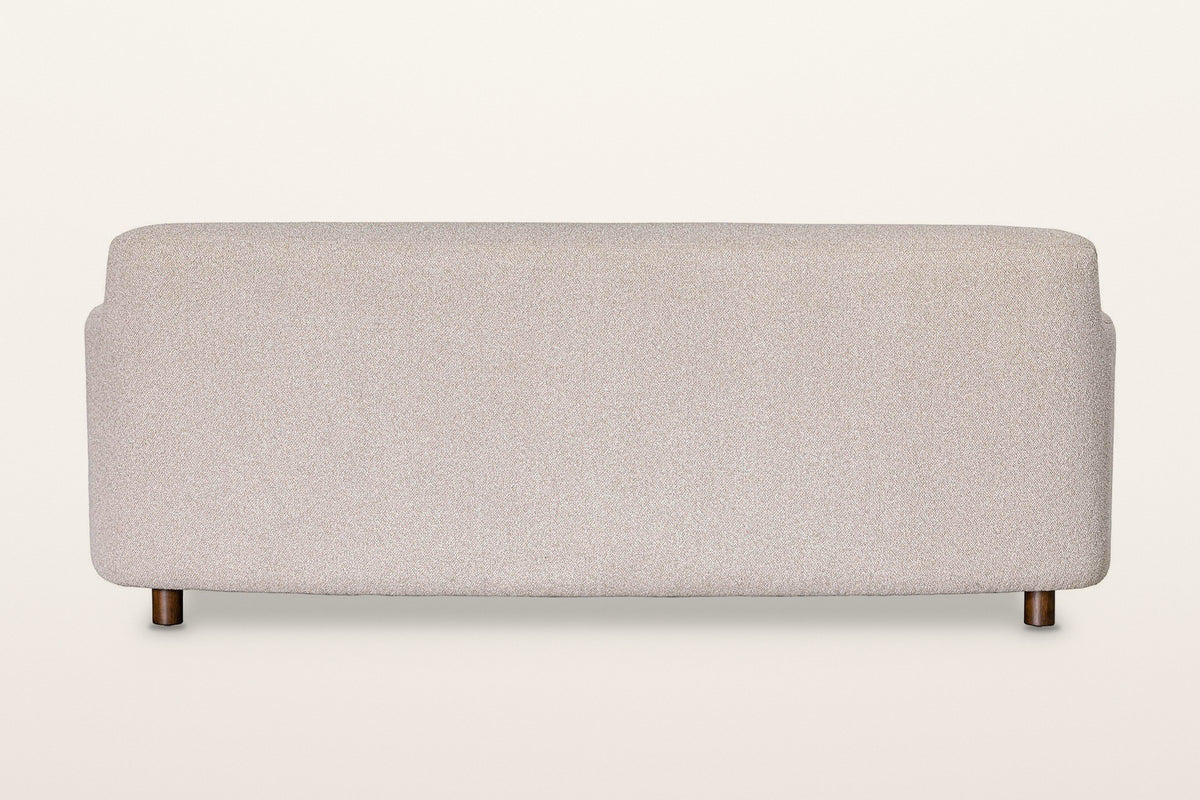 Back of the Ripatransone sofa in Beige on a warm white studio backdrop: a plain upholstered back with a soft curved top
