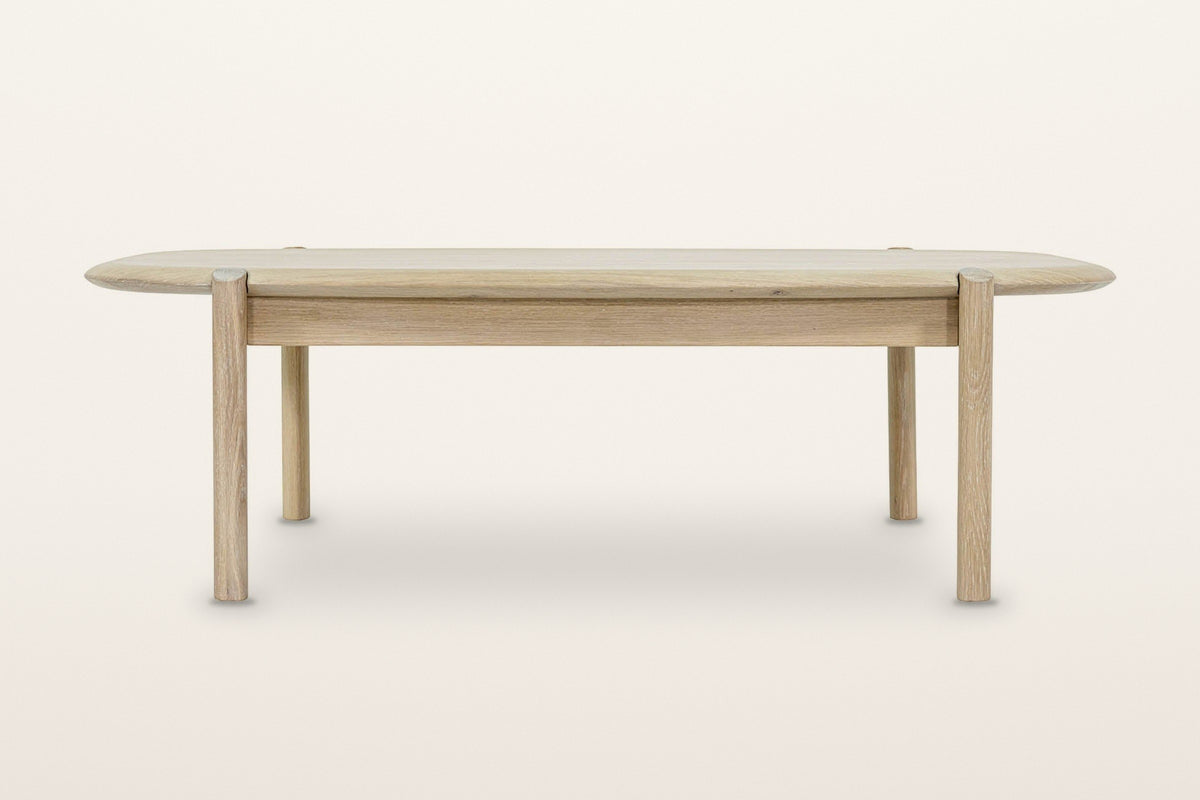 Rivello coffee table in Light Oak from the front on a warm white studio backdrop: legs set in from the rounded ends